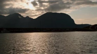 Bir dağ gölünün üzerinde gün batımının nefes kesici bir görüntüsü, gökyüzünün ve suyun dramatik renklerini gözler önüne seriyor.