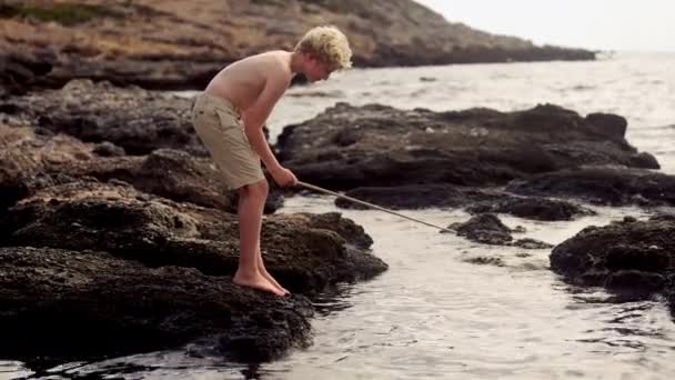 Zdjęcie Boku Młodego Chłopca Stojącego Twardej Formacji Skalnej Żarliwie Łowiącego — Wideo stockowe