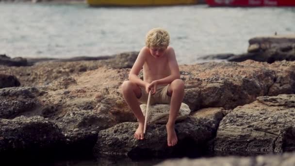 Kayalık Bir Kıyı Şeridinde Oturan Bir Çocuk Gündüzleri Oltayı Olta — Stok video