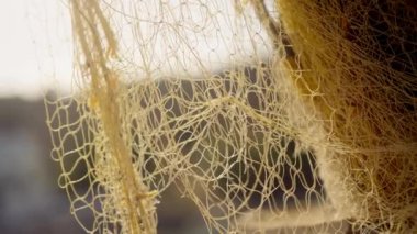 Bu temel balıkçılık aletinin dokusunu ve işçiliğini gözler önüne seren canlı sarı bir balıkçı ağının gündüz yakın çekim görüntüsü