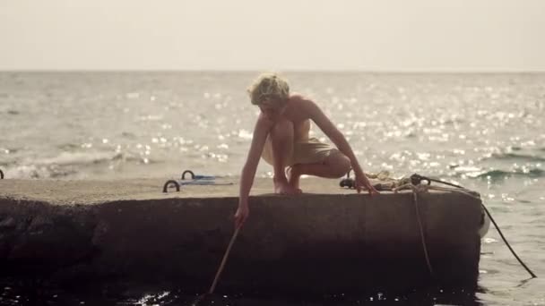 Beton Bir Platformda Çömelmiş Bir Çocuk Denizin Parıldayan Zemininde Derin — Stok video