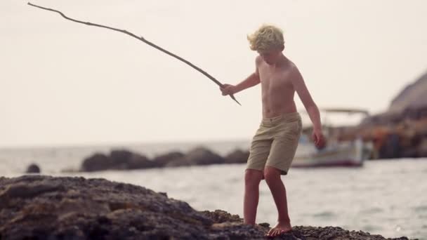 Niño Mueve Cuidadosamente Largo Costa Rocosa Agarrando Palo Pescar Mientras — Vídeos de Stock