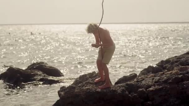 Ένα Αγόρι Που Στέκεται Πάνω Βράχους Σχολαστικά Ετοιμάζει Δόλωμα Μέσα — Αρχείο Βίντεο