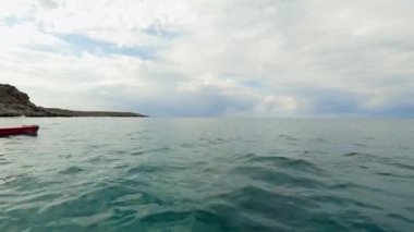 Yalnız bir çocuk kanosuyla Akdeniz 'in sakin sularında kürek çeker. Ufkun engin genişliğine karşı çerçevelenmiştir.