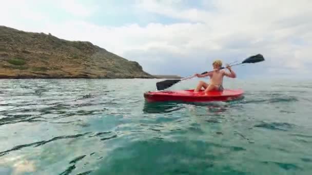 昼間のクレタ島の地中海岸に沿って彼のカヤックをパドル — ストック動画