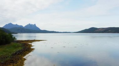 İHA görüntüsü, bulutlu gökyüzünün altında Hamaroy 'un sıradağlarının arka planına karşı alg kümeleriyle bir göl yakalıyor.