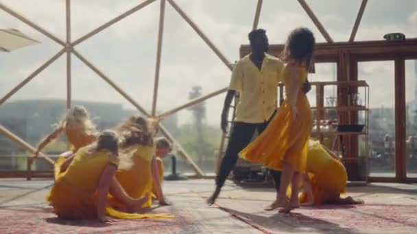 身着橙色服装的人们 在一个地热穹顶的充满激情的环境中 通过生动活泼的舞姿 热情地展现自己的情感 — 图库视频影像