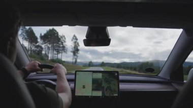 Statik çekim kusursuz bir araba yolculuğunu yakalar. Bir adam GPS 'i kullanarak rahatça yol alırken güvenli bir şekilde manzaranın tadını çıkarır.