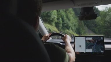 Elektrikli araç kullanan bir adam, GPS ile döşenmiş, ağaçlarla çevrili yeşil yollar boyunca sorunsuzca seyahat ediyor.