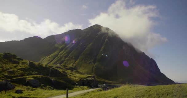 見事で印象的な山の背景にレンズフレアの視覚的な輝きをキャプチャする右から左へのパンニングショット — ストック動画