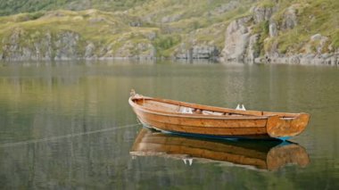 Gündüz vakti bir dağ gölünün el değmemiş sularında bir tekne yavaşça sürüklenir.