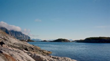 Durağan bir çekim Henningsv 'in kayalık kıyılarının engebeli cazibesini yakalar açık mavi gökyüzünün arka planına kurulmuş