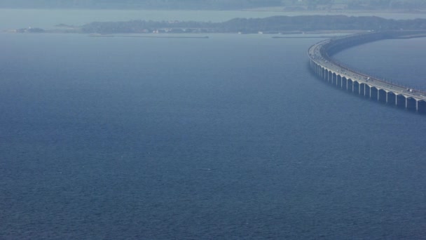 デンマークの昼間の間にグレートベルト橋を渡る交通の流れを捉えるために左から右に移動する空中パンショット — ストック動画