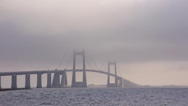デンマークの象徴的なグレートベルト橋を優雅に受け入れる霧雲の静的なショット — ストック動画