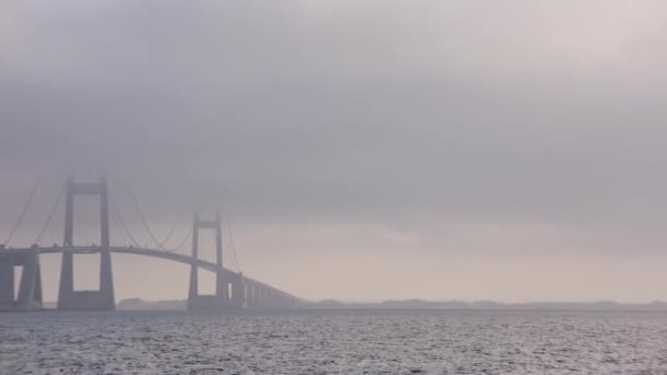 右から左に移動するパンショットは デンマークの日の柔らかい危険の下でグレートベルト橋の優雅さをキャプチャします — ストック動画