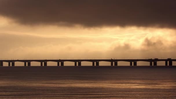 右から左に移動するパンショット デンマークのグレートベルト橋の魅惑的な日没シルエットをキャプチャ — ストック動画