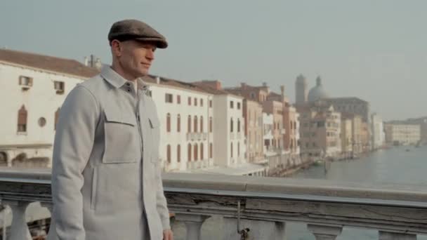 Ένας Άντρας Γκρι Καπέλο Και Ελαφρύ Μπουφάν Περπατά Μια Γέφυρα — Αρχείο Βίντεο