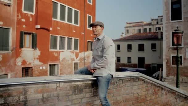Man Wearing Grey Hat Sits Ledge Bridge While Admiring Surrounding — Stock Video