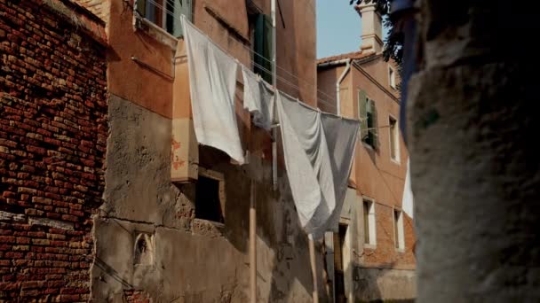 街の歴史的な雰囲気の背景に対して穏やかな風に揺れる原始の白いリネンの屋外乾燥 — ストック動画