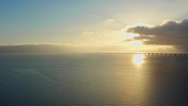 日が昇る象徴的なグレートベルト橋の上を歩く避難所を撮影したドローンショット — ストック動画