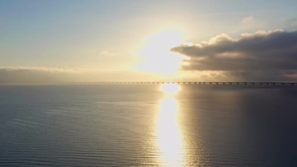 飛行機を撮影したドローンショットは 日の出中に象徴的なグレートベルト橋の上に優雅に上昇します — ストック動画
