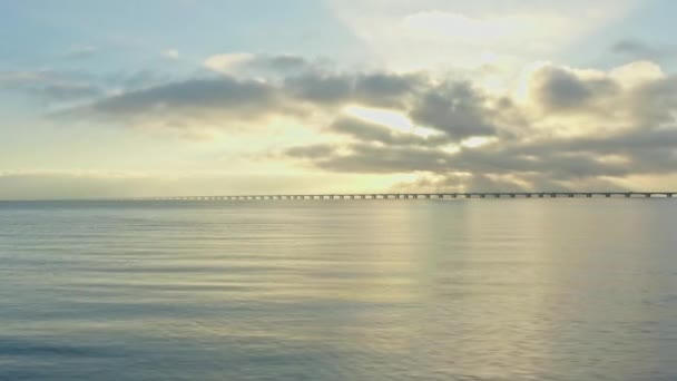 デンマークのグレートベルト橋の雄大なシルエットを 見事な日の出の背景にスムーズに滑らかに滑らかに滑走するドローン — ストック動画