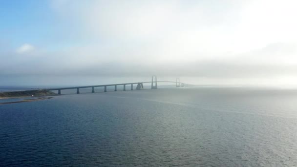 遠くの象徴的なグレートベルト橋を捉えた穏やかな海に優雅に輝く魅惑的なドローン映像 — ストック動画