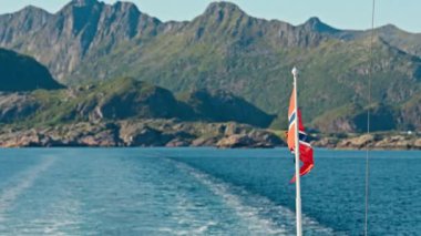 Norveç posta bayrağının nefes kesen bir dağ zeminine karşı feribotta gururla dalgalandığı POV stok videosu.