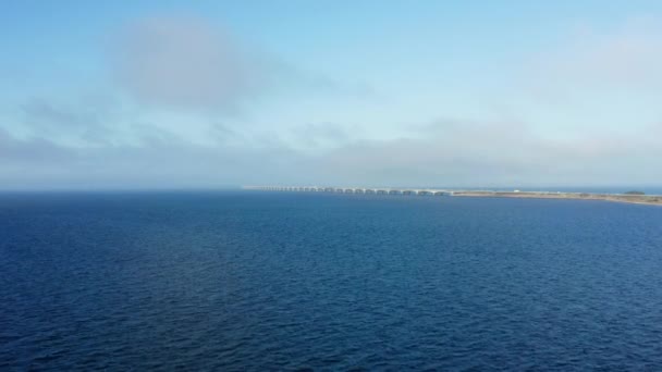 ドローンは穏やかな青い水の上に優雅に浮かび デンマークの象徴的なグレートベルト橋をフレーム — ストック動画