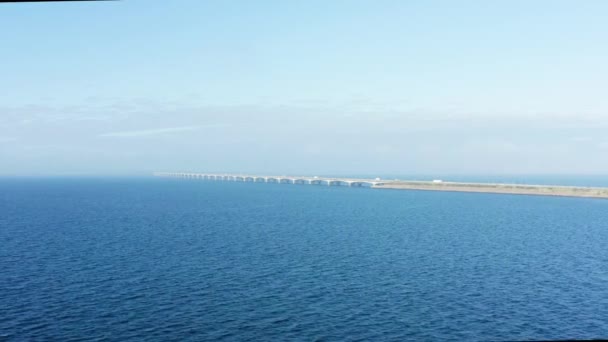 ドローンは遠くの象徴的なグレートベルト橋を眺めながら 広大な青い海の左側に優雅に輝いています — ストック動画