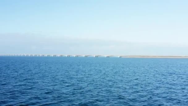 ドローンは優雅に右にグライドし 広大な青い海と島に接続された象徴的なグレートベルト橋を明らかにします — ストック動画