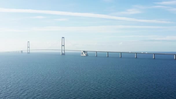 ドローンが右に滑り 静かな海と広大な空の下で象徴的なグレートベルト橋をキャプチャする — ストック動画