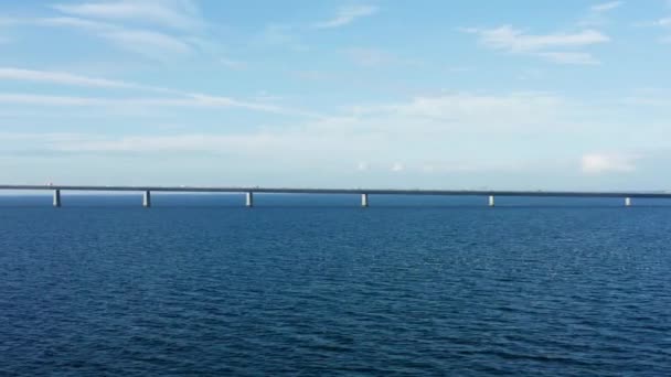 一架无人驾驶飞机优雅地滑向左边 占领了横跨平静水域的大贝尔特桥 — 图库视频影像