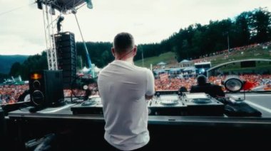Eğik görüş, açık hava ortamının ortasındaki sanatçının enerjisini ve yaratıcılığını vurgulayan bir DJ 'i açık havada konser verirken yakalıyor.