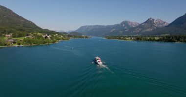 Avusturya dağlarındaki sakin mavi sularda seyreden bir teknenin insansız hava aracı görüntüsü.