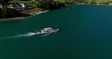 Avusturya 'nın nefes kesen gölünde seyreden bir teknenin insansız hava aracı görüntüleri. Etrafı görkemli zirvelerle çevrili.