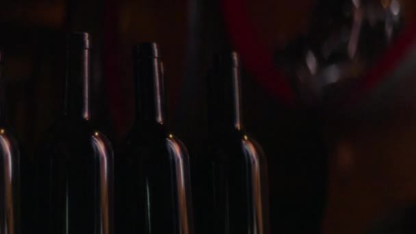 ワイナリー内の表面に点滅ライトが点滅し ぼやけた背景に設定されたダークカラーのワインボトル — ストック動画