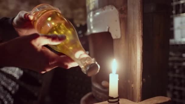 Крупный План Руки Человека Держащего Бутылку Вина Возле Зажженной Свечи — стоковое видео