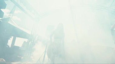 Güneş gözlüklü bir kadını sahnede dumanla çevrili büyüleyici bir şekilde dans ederken gösteren bir el kamerası görüntüsü.