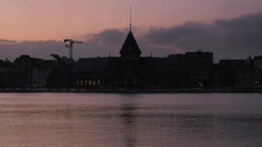 Gün batımı gökyüzü Aarhus Gümrük Evi 'nin üzerine çöker. Rıhtımın el değmemiş manzarası ve alacakaranlıkta binaların üzerinde yükselen bir vinç sunar.