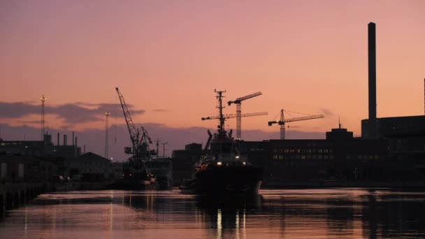 日落时分 一艘拖船在落日的温暖色调下 在高耸的起重机和工业建筑的背景下 驶过奥胡斯港 — 图库视频影像