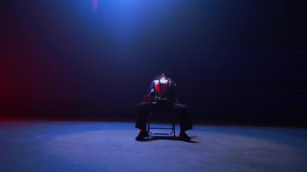 ハンドヘルドショットは優雅にズームアウトし 青と赤のレーザーの魅惑的な光に浴したダンサーの魅惑的な椅子ダンスをキャプチャします — ストック動画