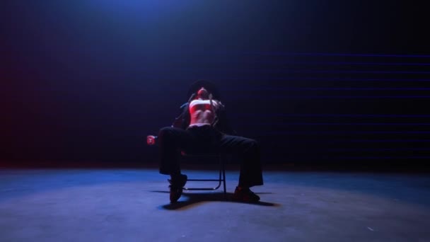 ハンドヘルドショット シームレスにズームアウトし 青と赤のレーザーの輝く光に浴した女性の魅惑的な椅子ダンスをキャプチャ — ストック動画
