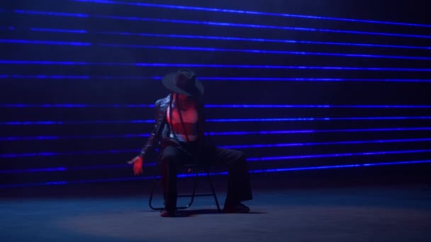 完全な静的なショットは青色レーザーライトの魅惑的な背景に対して才能のある女性の椅子のダンスをキャプチャします — ストック動画