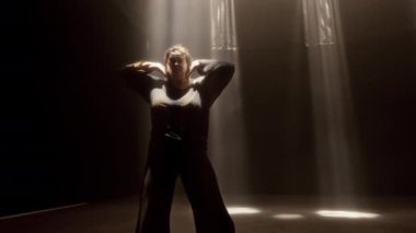 Yetenekli bir kadın, stüdyo ışıklarının altında el kamerasıyla zarif bir şekilde dans eder. Her hareketinde yeteneğini ve ifadesini sergiler.