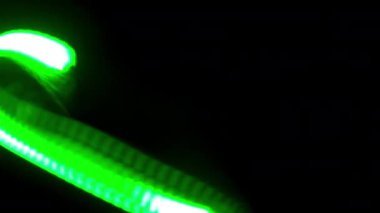 Yeşil ışık parıldayan enerjiyle karanlığın içinde dans ediyor.