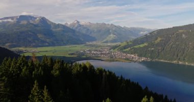Havadan çekilen bir görüntü, bulutlu gökyüzünün altında yemyeşil ve görkemli dağlarla çevrili sakin bir göl kıyısındaki resim gibi Avusturya şehrini yakalıyor.