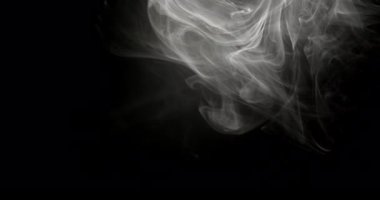 Siyah arkaplandan yavaşça yayılan beyaz duman zerreleri havada kıvrılır.