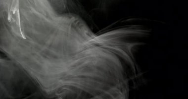 Siyah arkaplanın her iki tarafında beyaz duman perileri belirir. Işıklar havada süzülürken soyut desenleri vurgular.