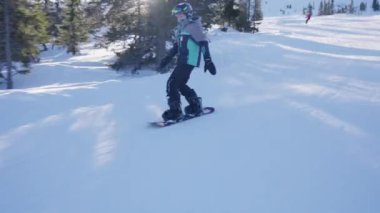 Genç bir çocuğun, snowboard yaparken gündüz eğlencesini kucakladığı bir fotoğraf.